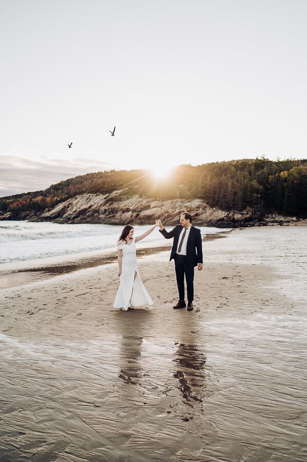 Bride and groom dancing on sand beach in acadia