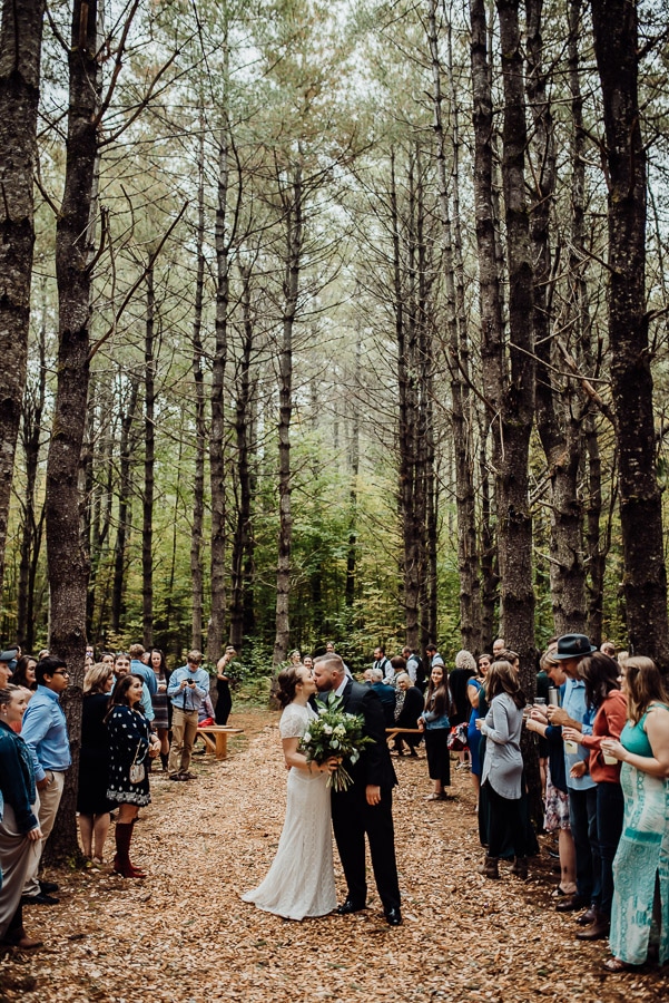 Bride and groom in woods wedding kissing