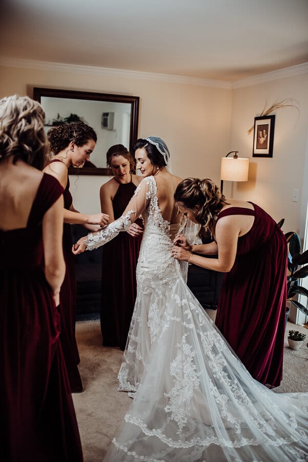Bridesmaids helping bride dress
