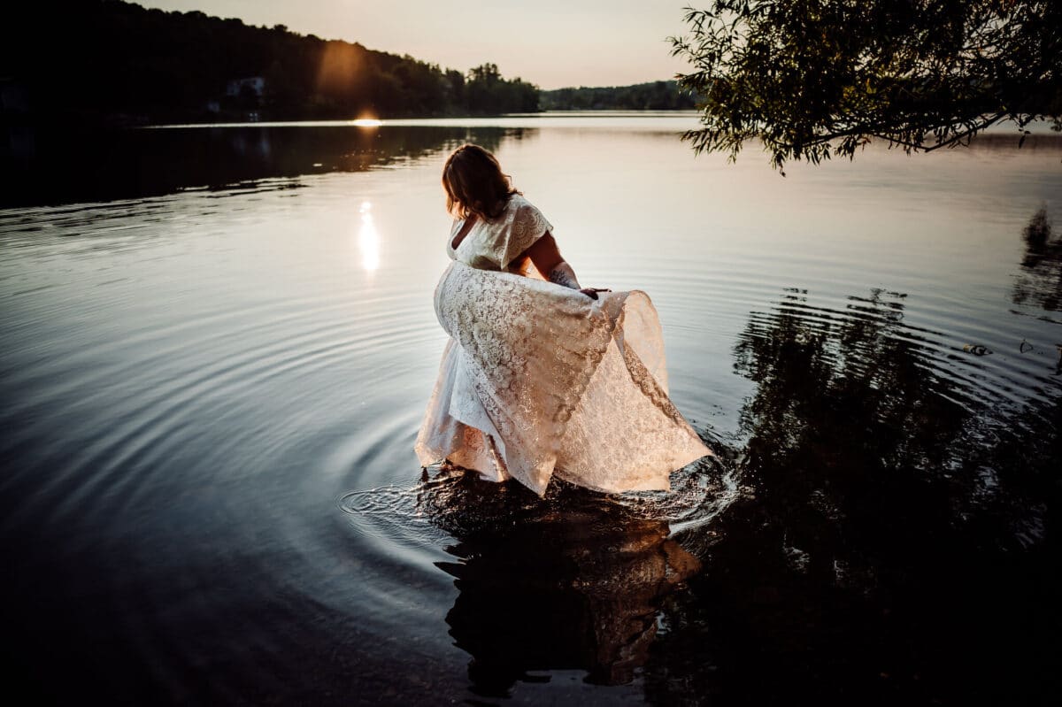 Pregnant woman wearing lace dress in lake