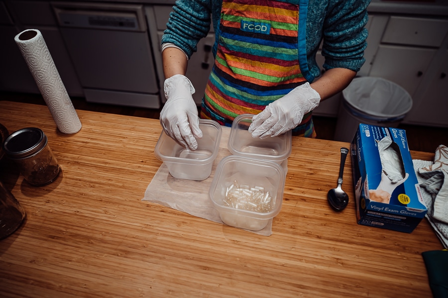 Gloved hands separating capsules in half