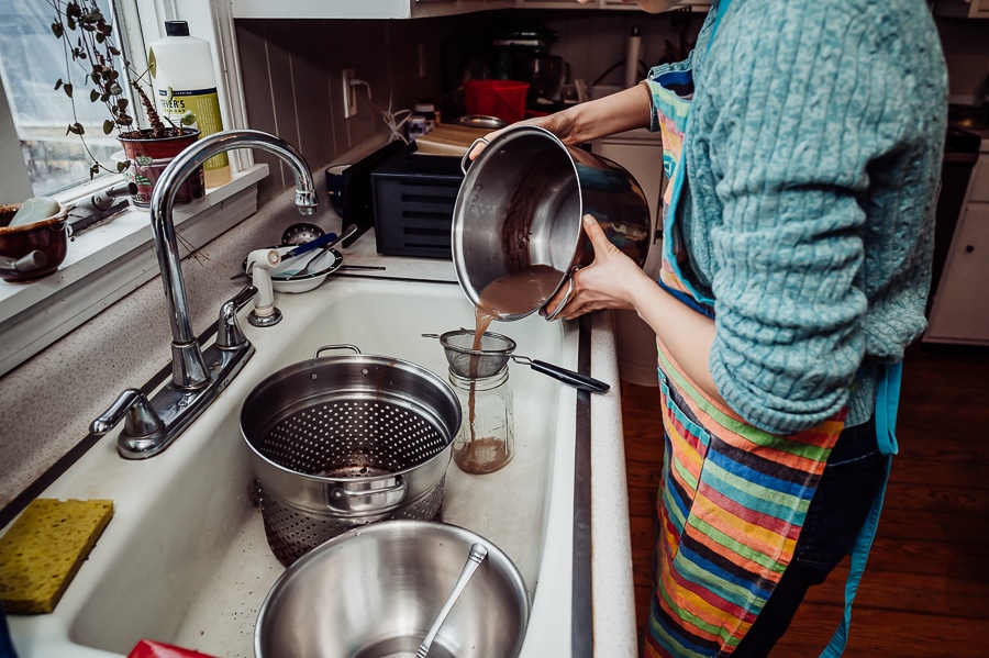 Woman pouring mothers broth into jar