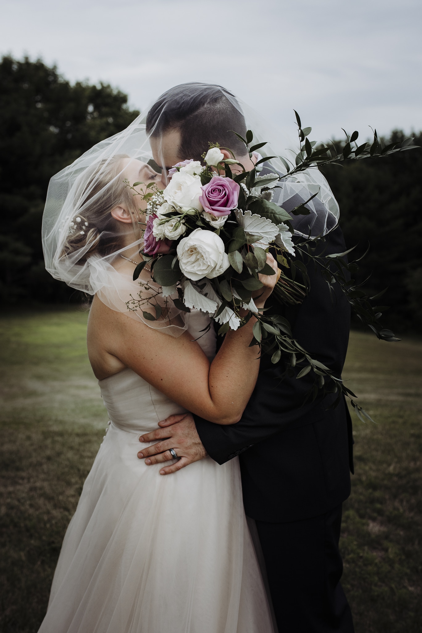 Bride and groom kissing behind bouquet at lucerne inn