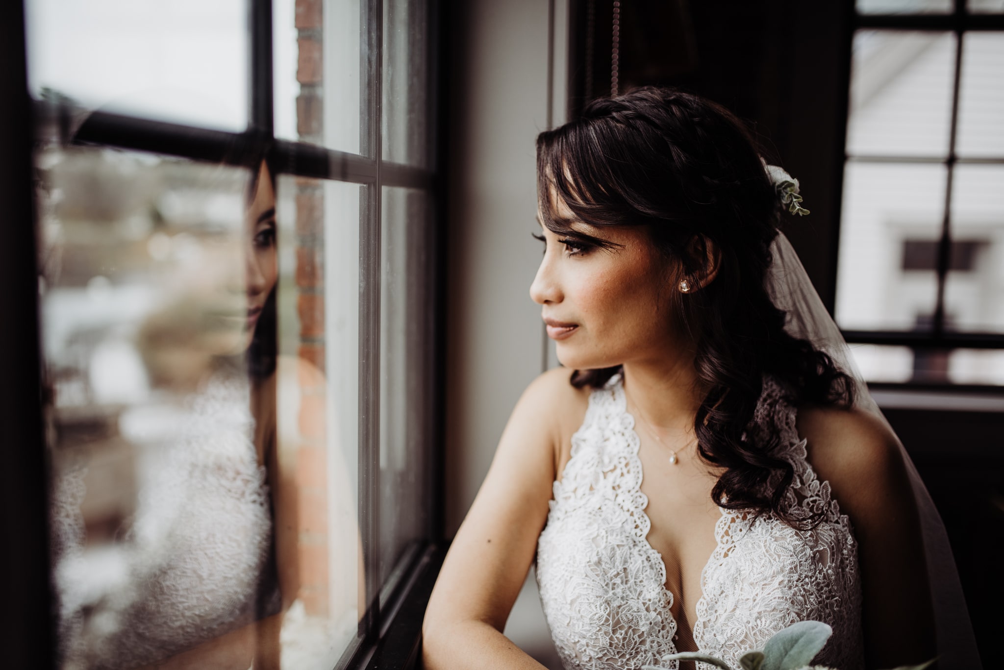 Bride looking out the mill window before wedding