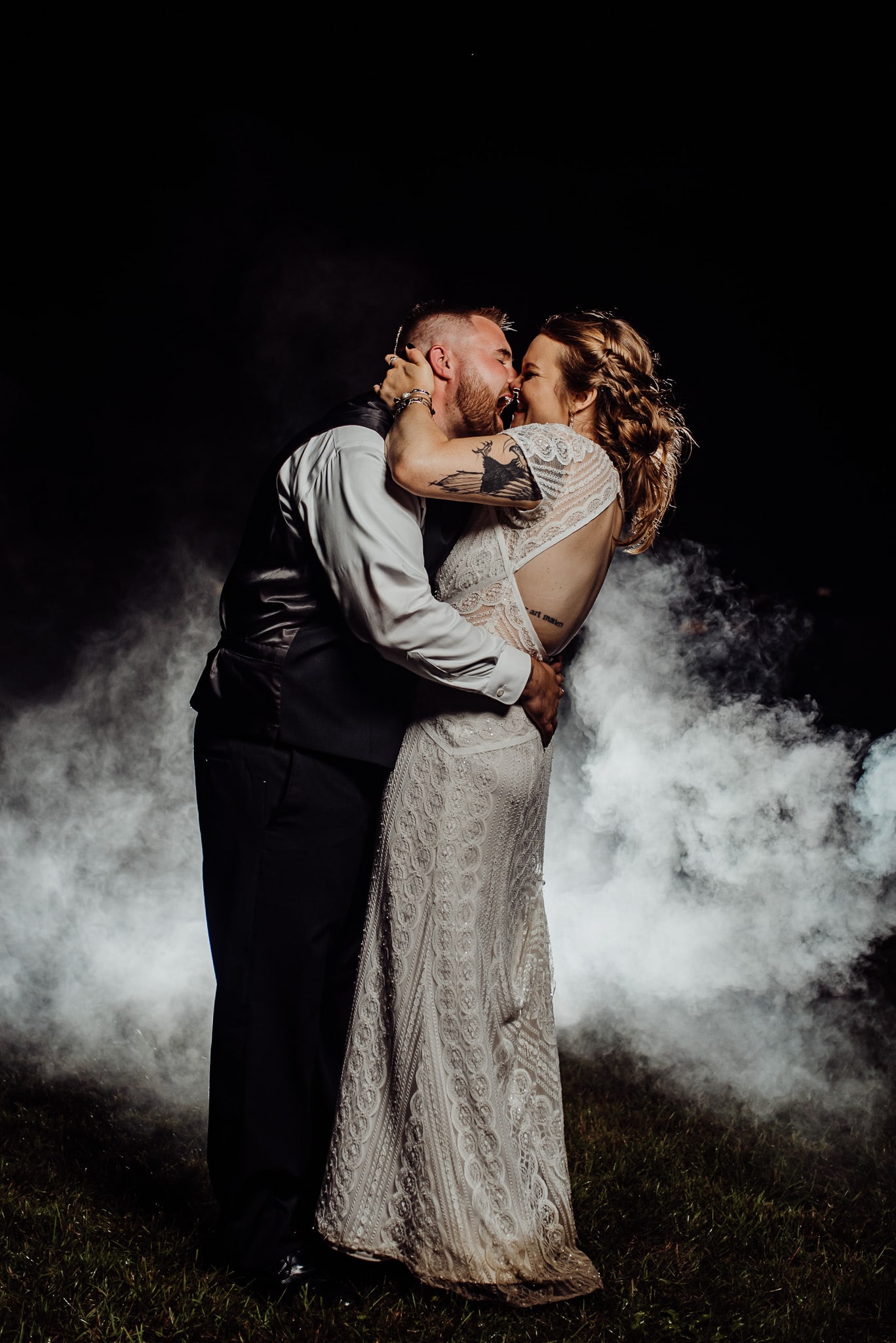 Bride and groom kissing in front of smoke