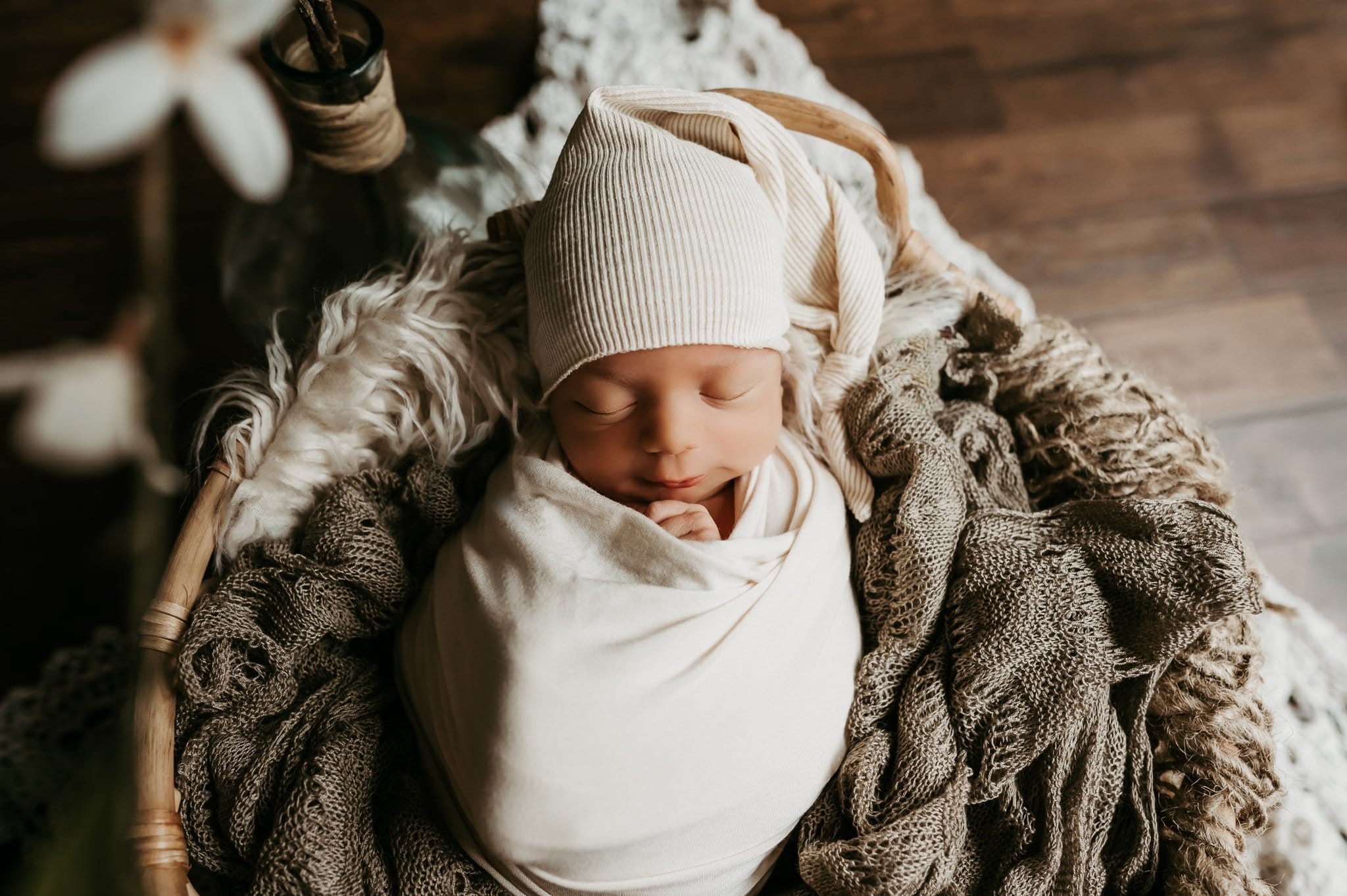 Newborn baby posed in basket with furr neutral colors