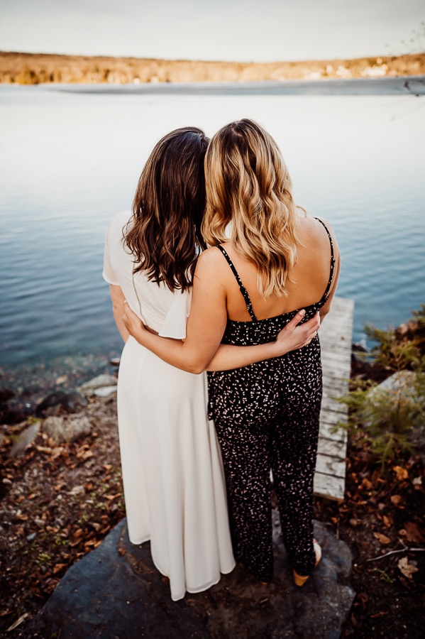 Two women hugging back to facing lake