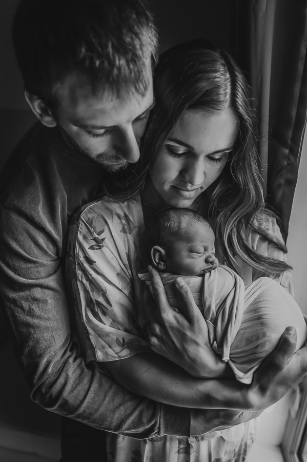 Black and white mother and father holding newborn baby