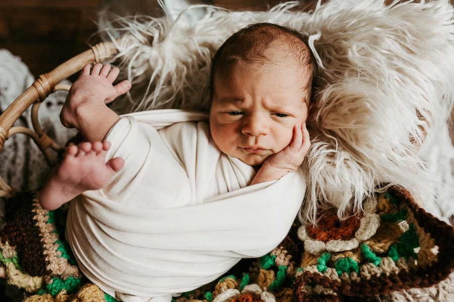 Newborn baby glaring at camera wrapped in white wrap