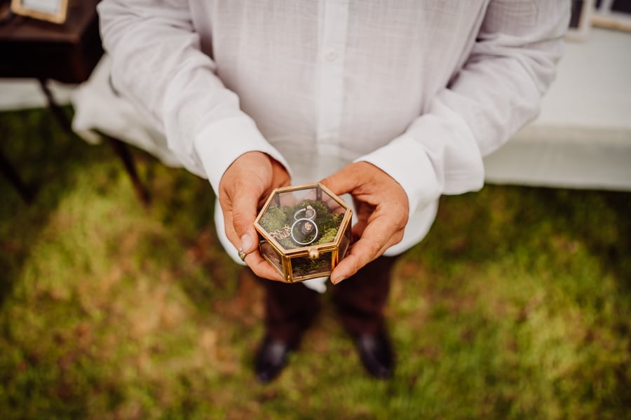 Groom holding rings in a glass box