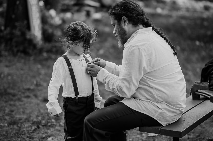 Father helping son fix suspenders before wedding