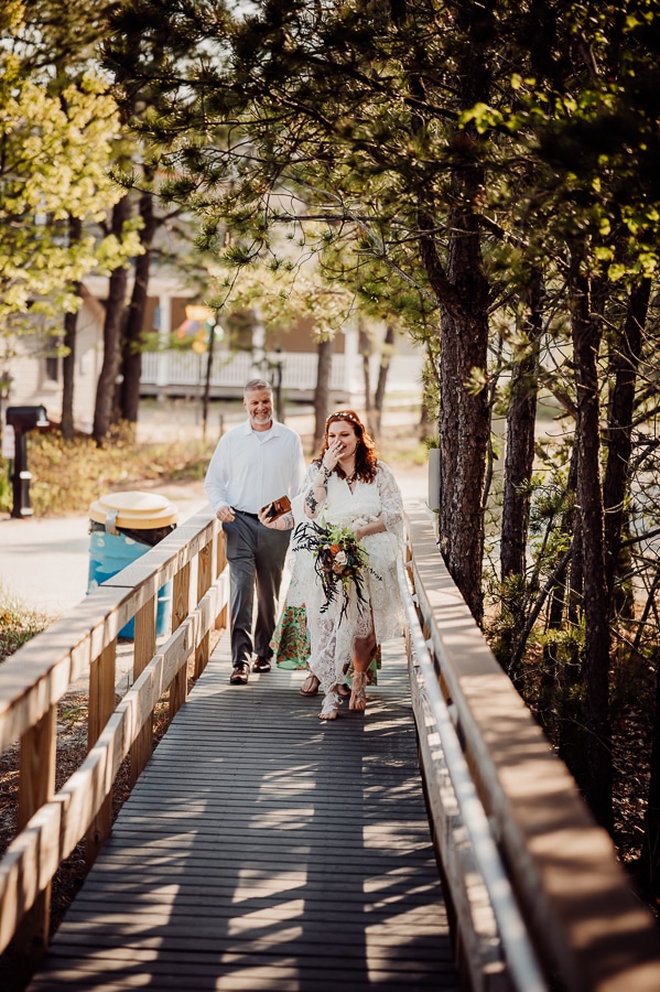 Father walking bride down boardwalk to beach wedding