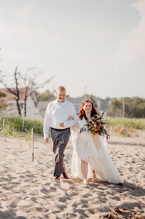 Father and bride walking to wedding on beach