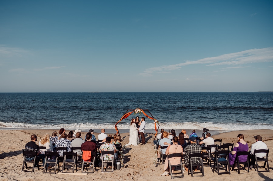 Wedding on the beach with people sitting in chairs