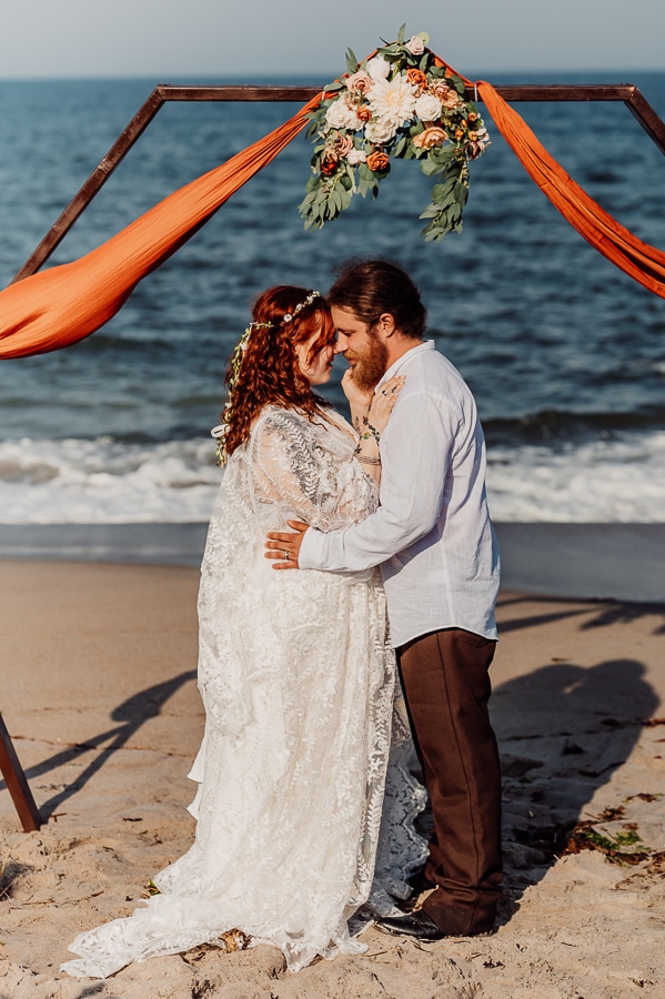 Bride and groom embracing after first kiss at the alter on the beach