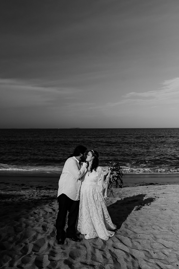 Black and white bride and groom kissing on beach
