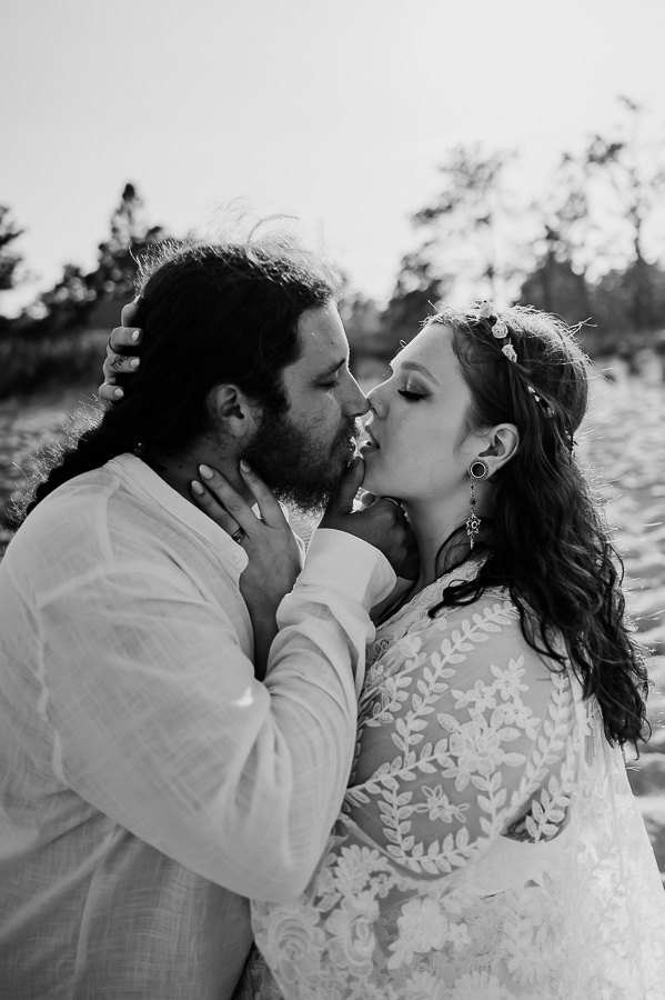 Black and white bride and groom kissing on beach