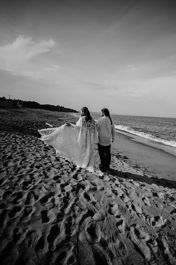 black and white bride and groom walking on the beach