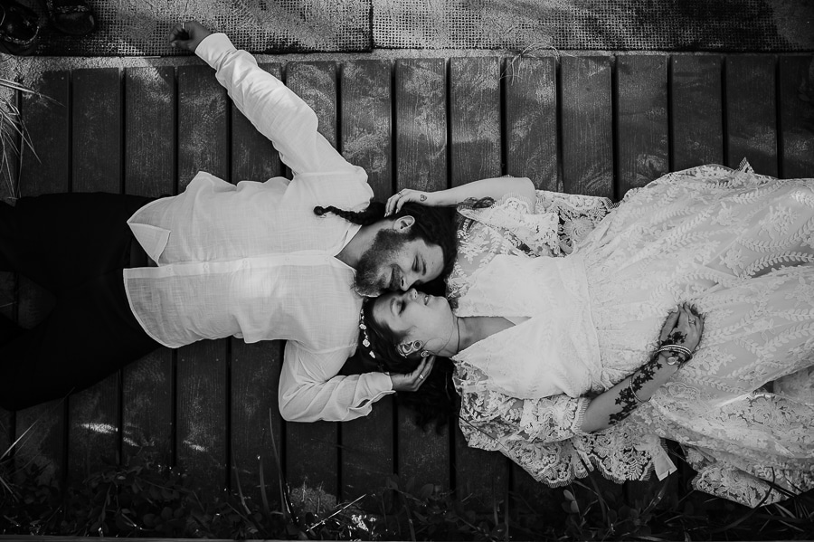 Black and white bride and groom laying on boardwalk looking at each other