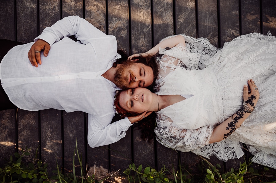 Bride and groom laying on wooden plank looking up