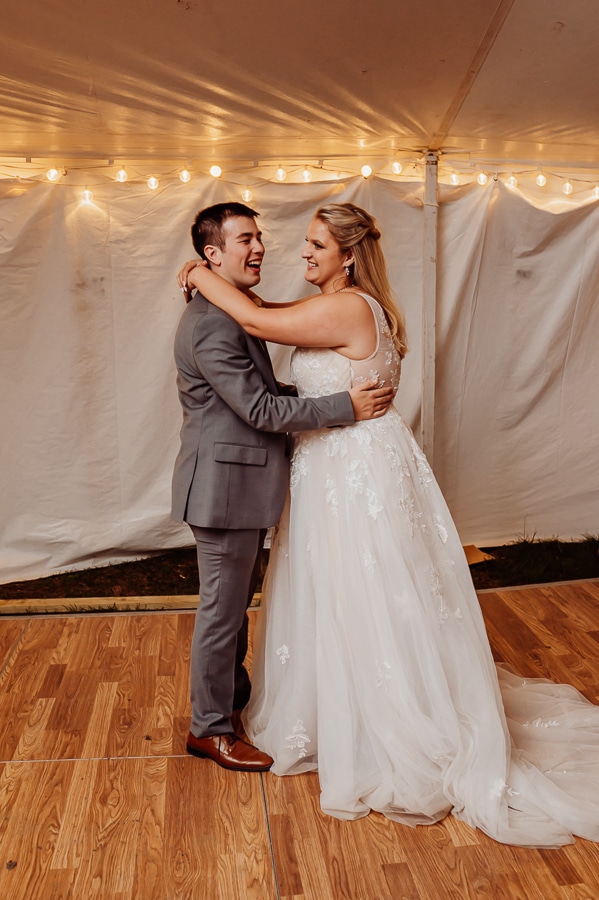 Bride and groom having first dance inside tent