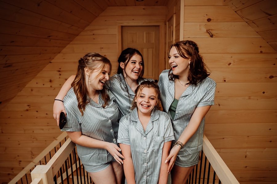 Bridesmaids laughing together inside wooden cabin in pajamas