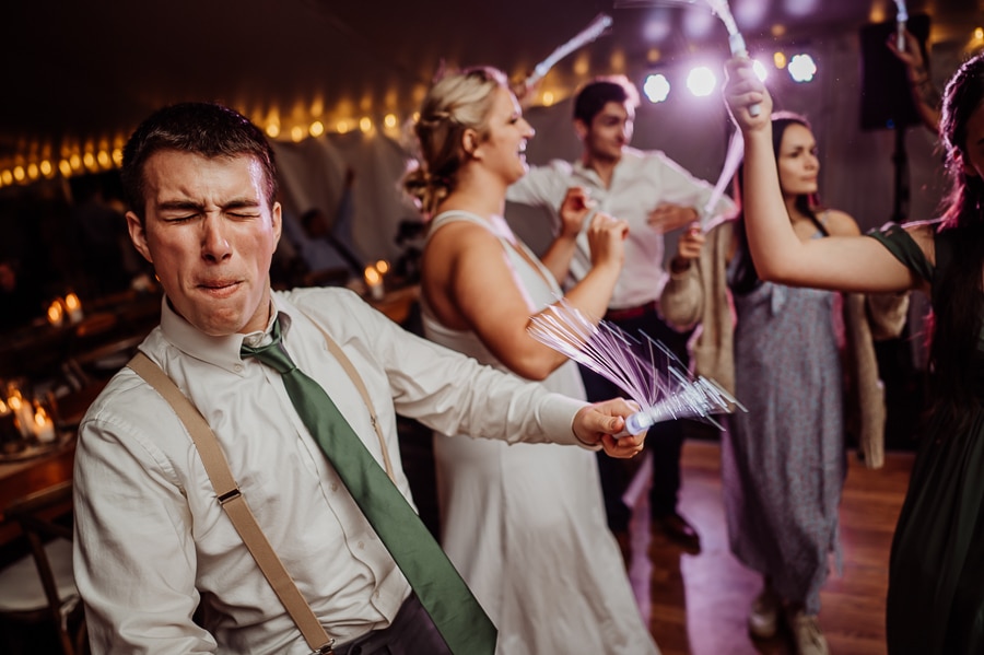 groom dancing on dance floor at wedding with bride in background