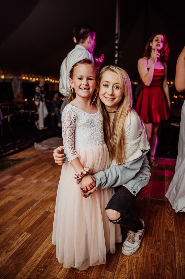Blonde woman in jean jacket with flower girl at wedding