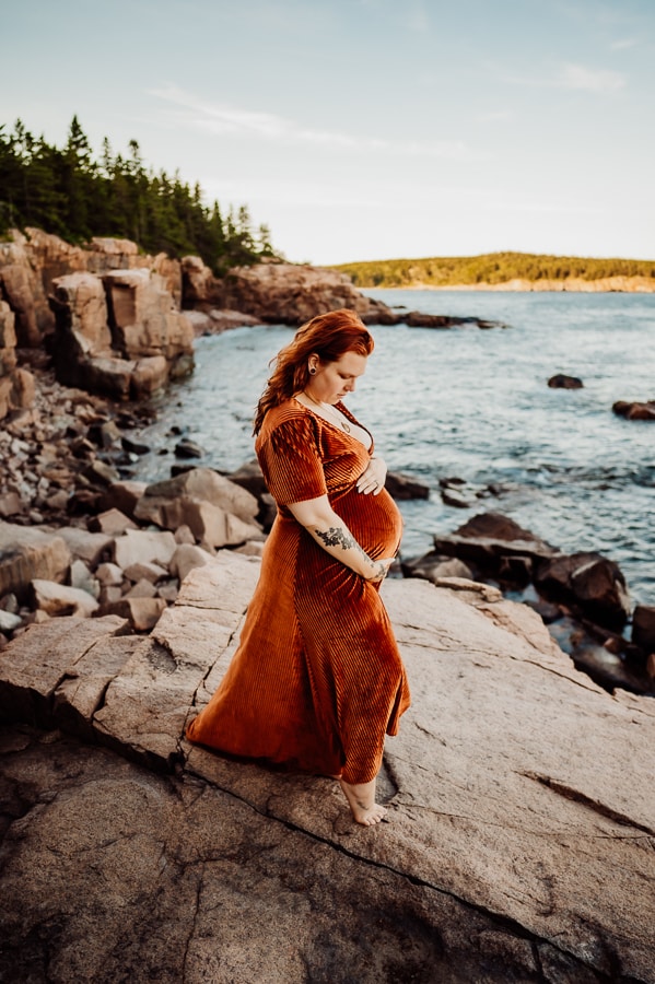 mother posing in orange dress on cliffs in acadia