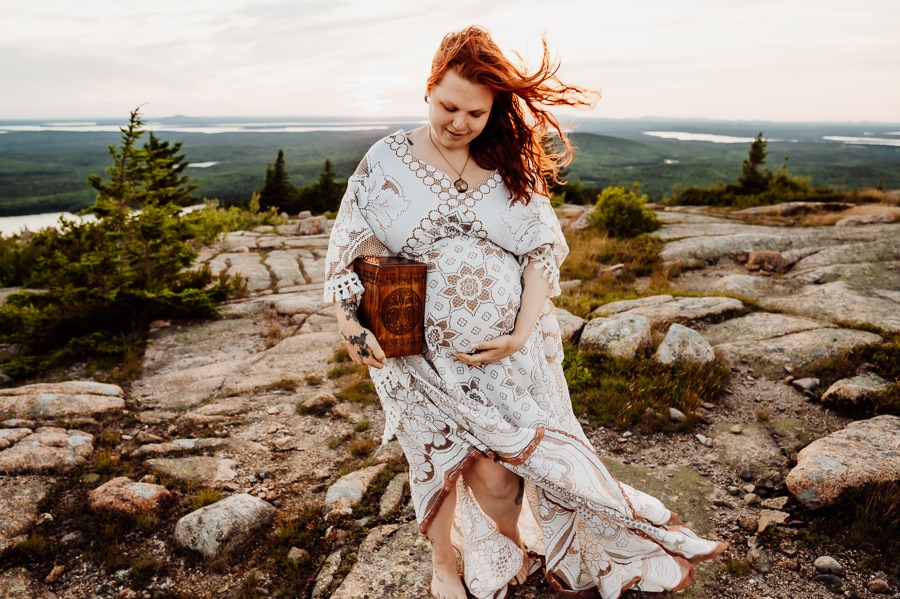 Pregnant woman holding stillborn urn on cadillac mountain