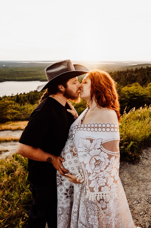 Man in cowboy hat holding wifes belly on cadillac mountain