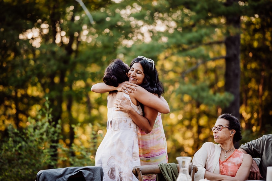 Two women with black hair hugging at reception