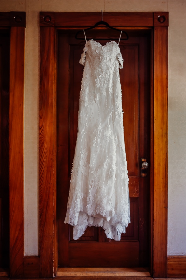 Wedding dress with textured flowers hanging on door