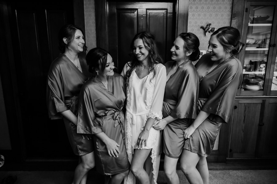 Bride and bridesmaids together in robes getting ready before wedding