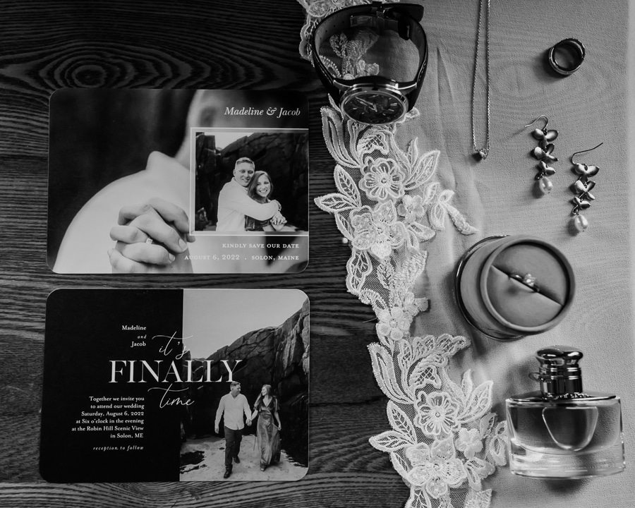 Black and white flat lay of wedding invitations and rings