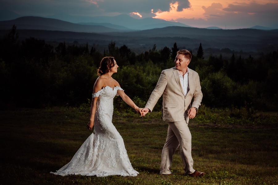 Groom and bride walking together at sunset in front of stunning sky
