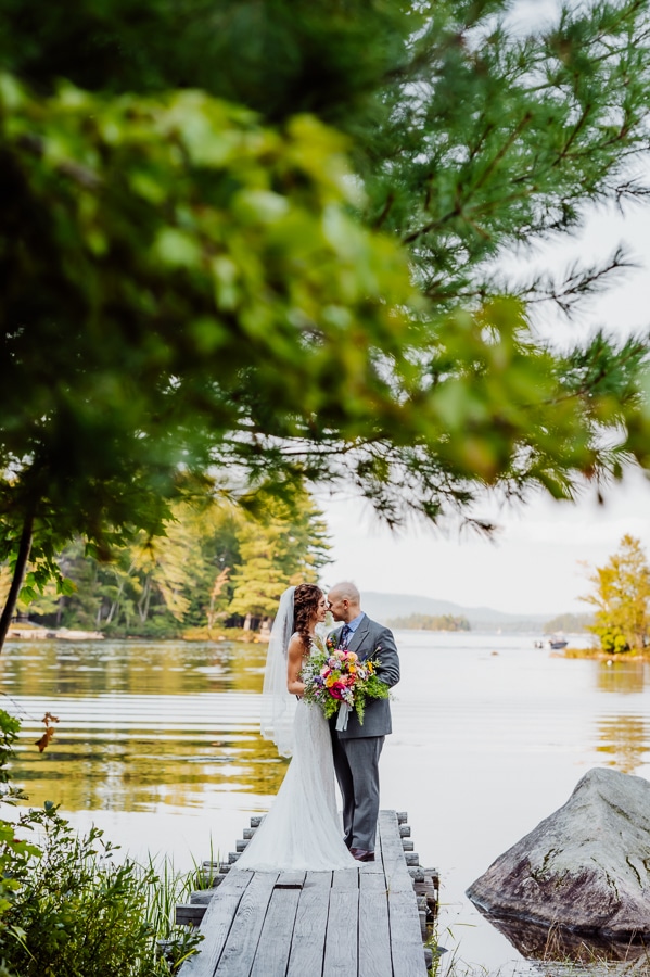 Bride and groom posing on dock at big moose inn