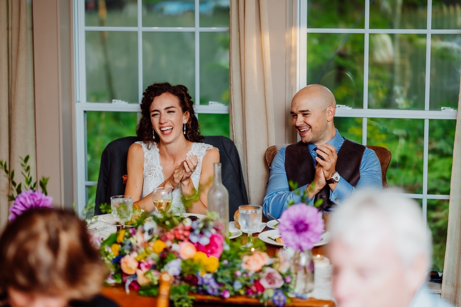 Bride and groom laughing at head table at big moose in wedding reception