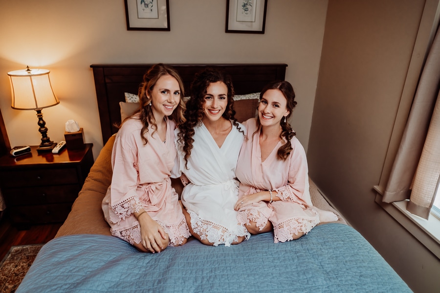 Bride and bridesmaids sitting on bed at big moose inn