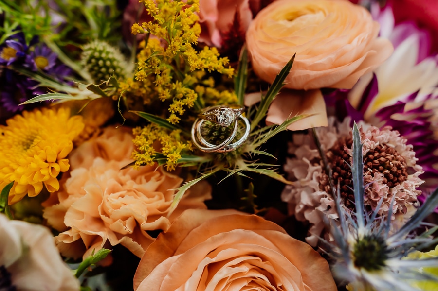 Wedding rings sitting on wedding bouquet flowers