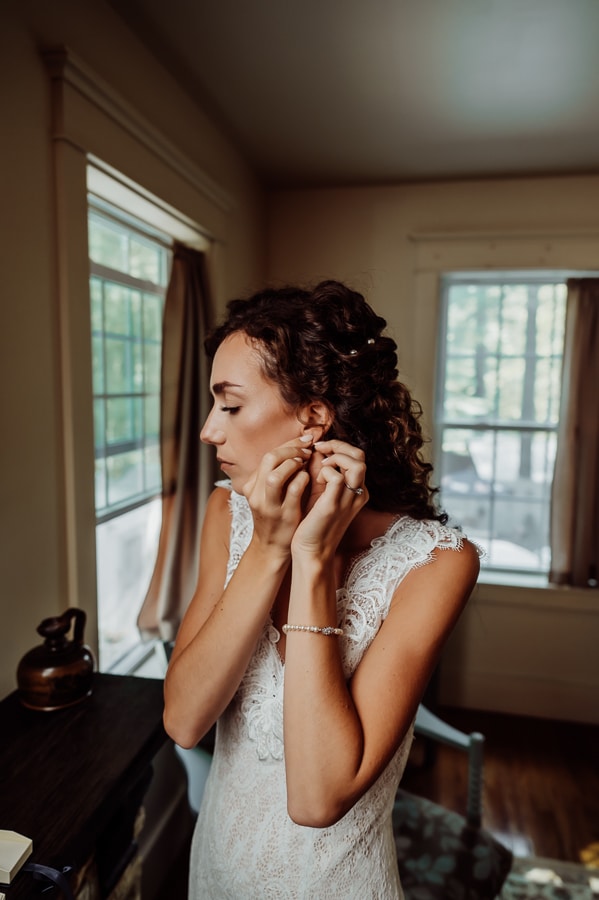Bride with curly hair putting earring in at big moose inn