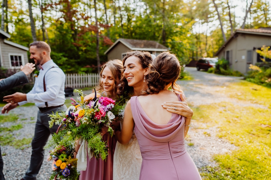 Bride hugging bridesmaids after wedding ceremony at big moose inn