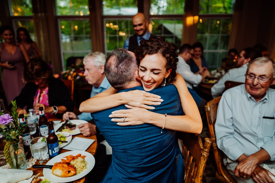 Bride hugging father at wedding reception in big moose inn dining room