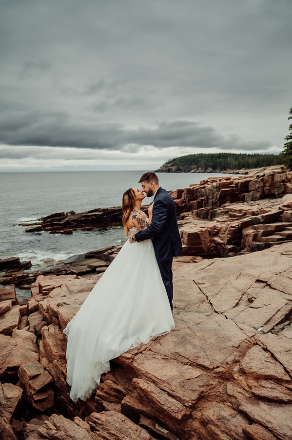 Bridal couple standing on thunder hole cliffs in acadia