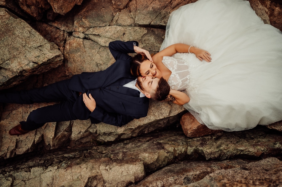 Bride and groom laying on rock cliff in Acadia National Park