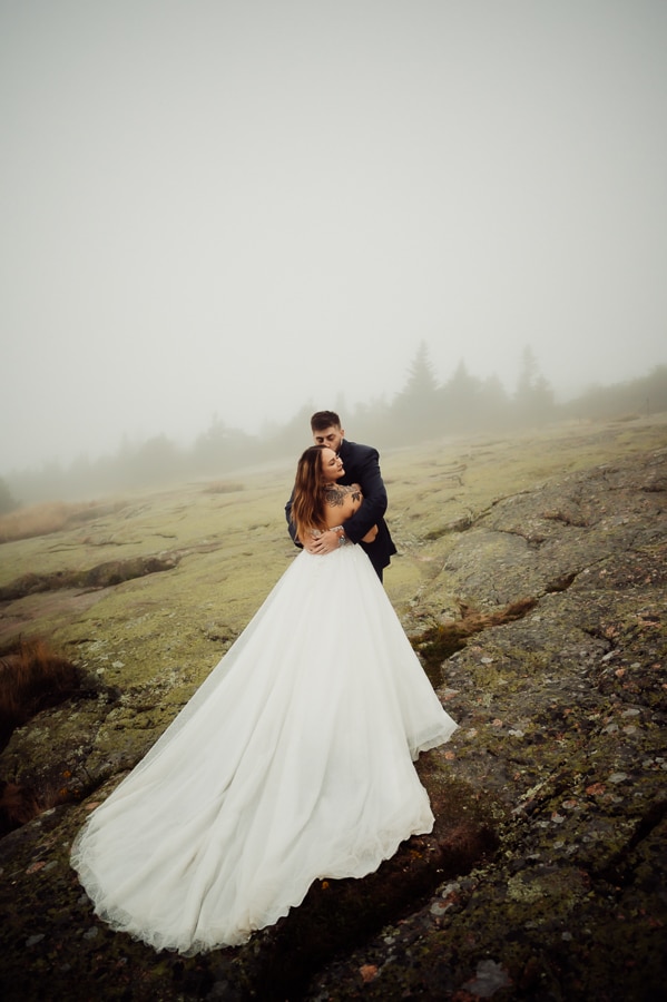 Bride and groom hugging on cliff side on cadillac mountain in fog