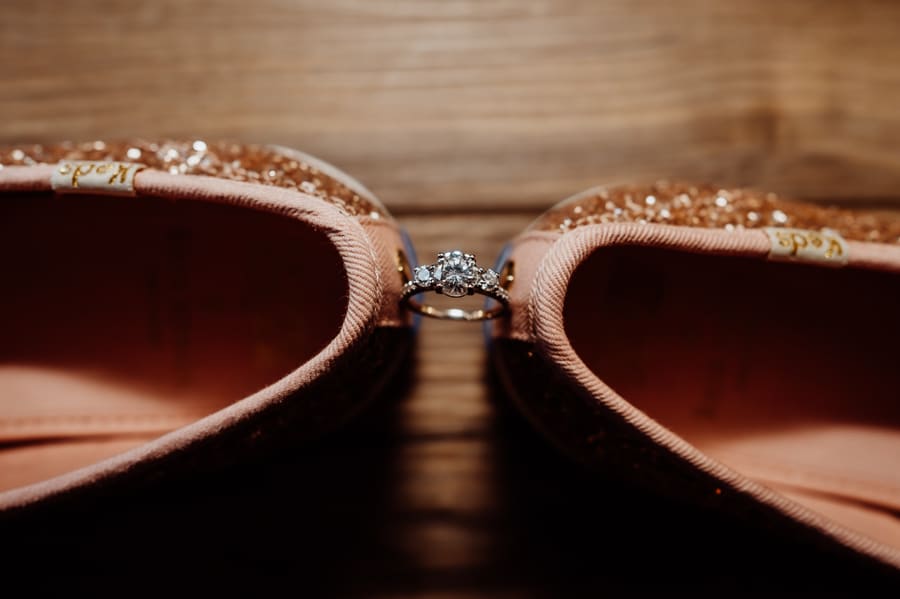 Engagement ring between two sparkly kate spade wedding shoes