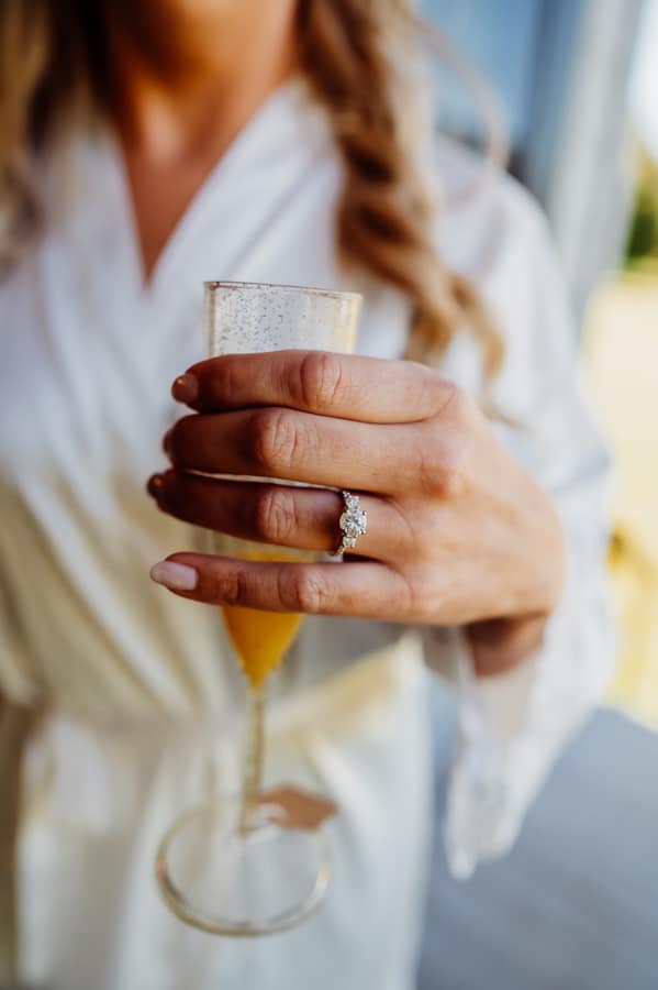 Woman wearing engagement ring holding champagne glass