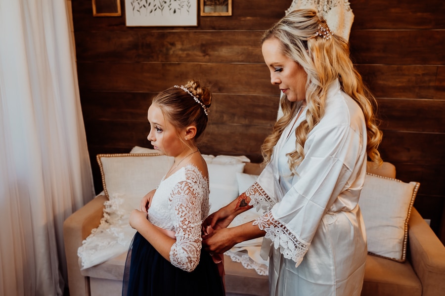 Bride helping flower girl tie the bow on her dress