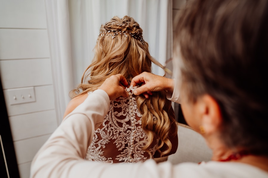 Woman fastening buttons on brides dress